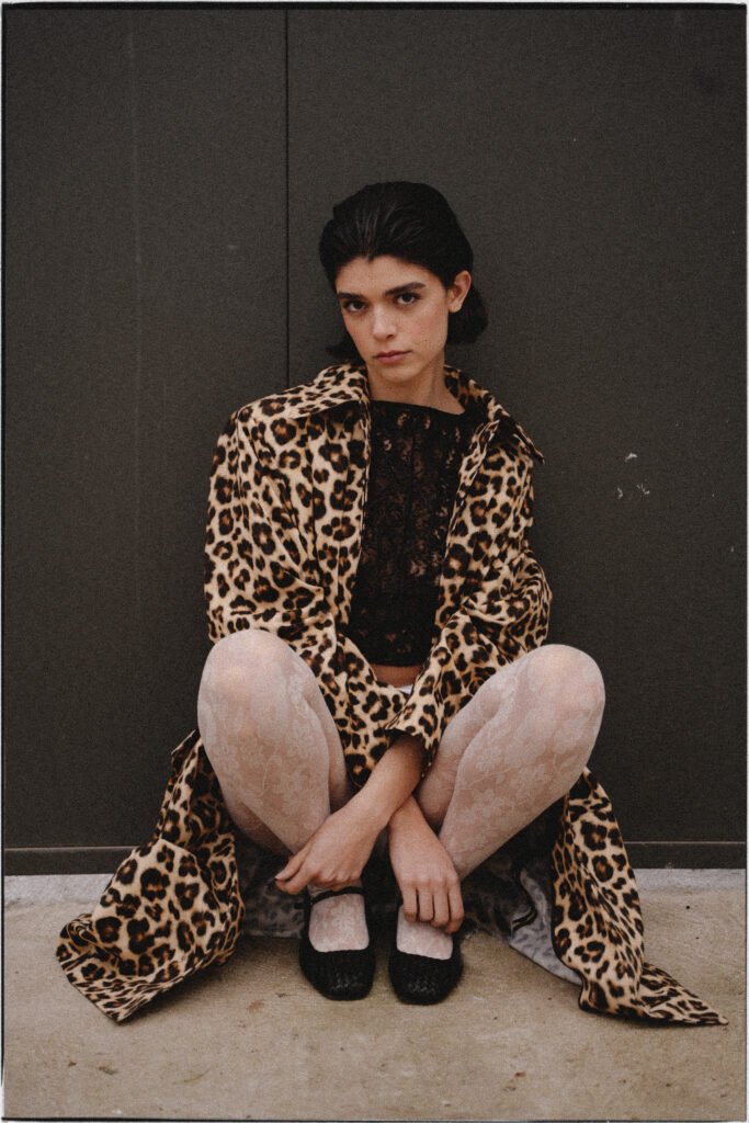 mujer agachada en el suelo con un abrigo de leopardo