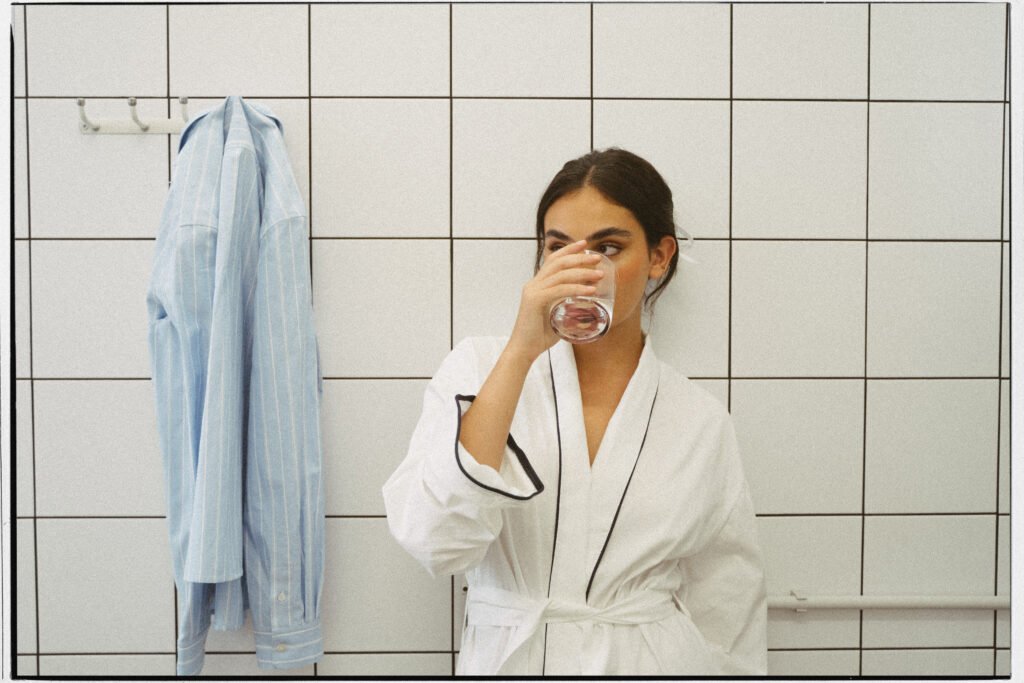 mujer en el baño bebiendo un vaso de agua
